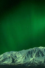 green northern lights above Alaska Range mountain